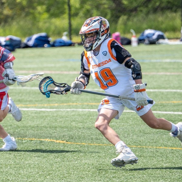 A youth lacrosse player cradling the ball on the run